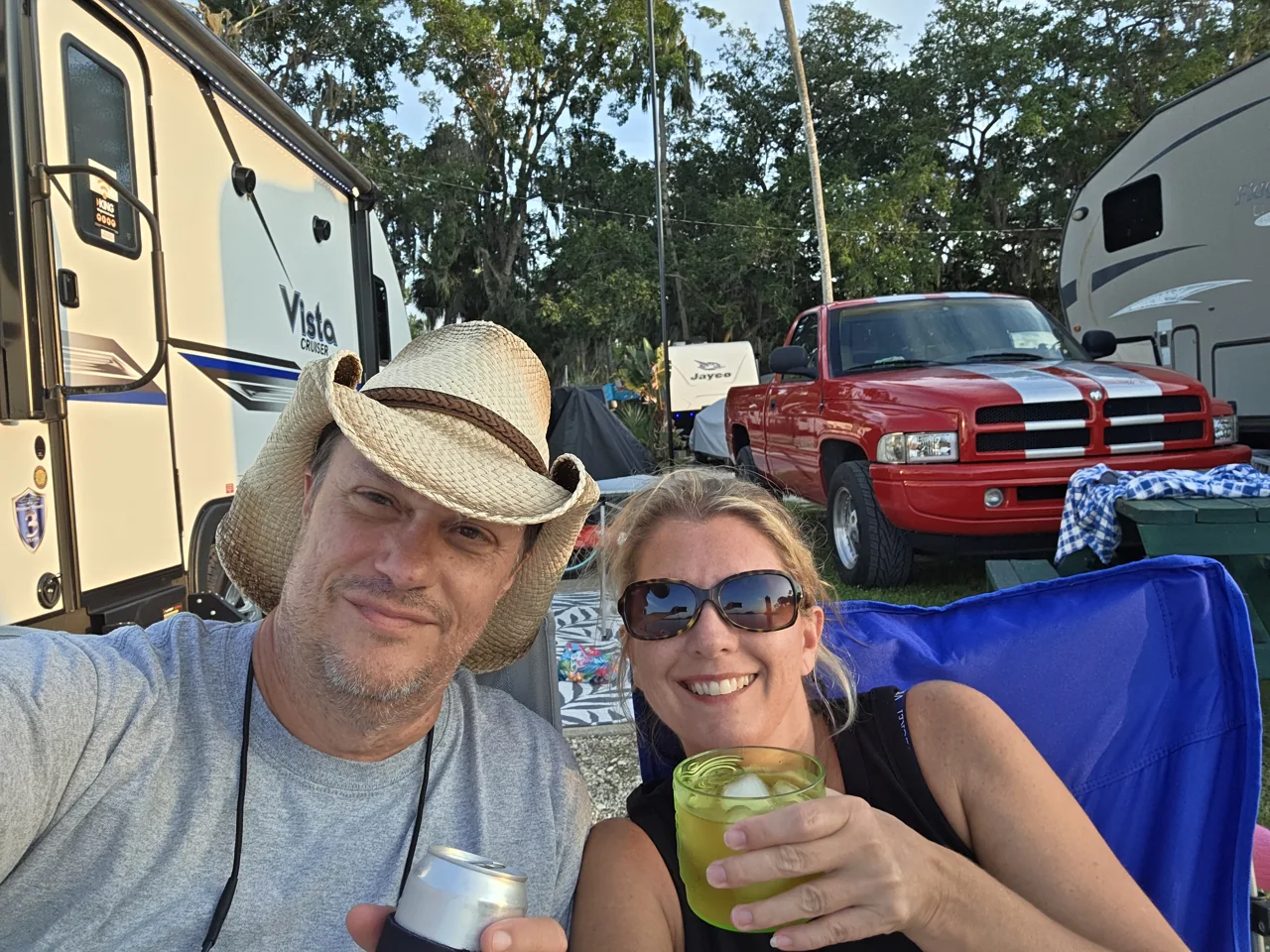 Chris and Tina relaxing in camping chairs beside their Vista Cruiser